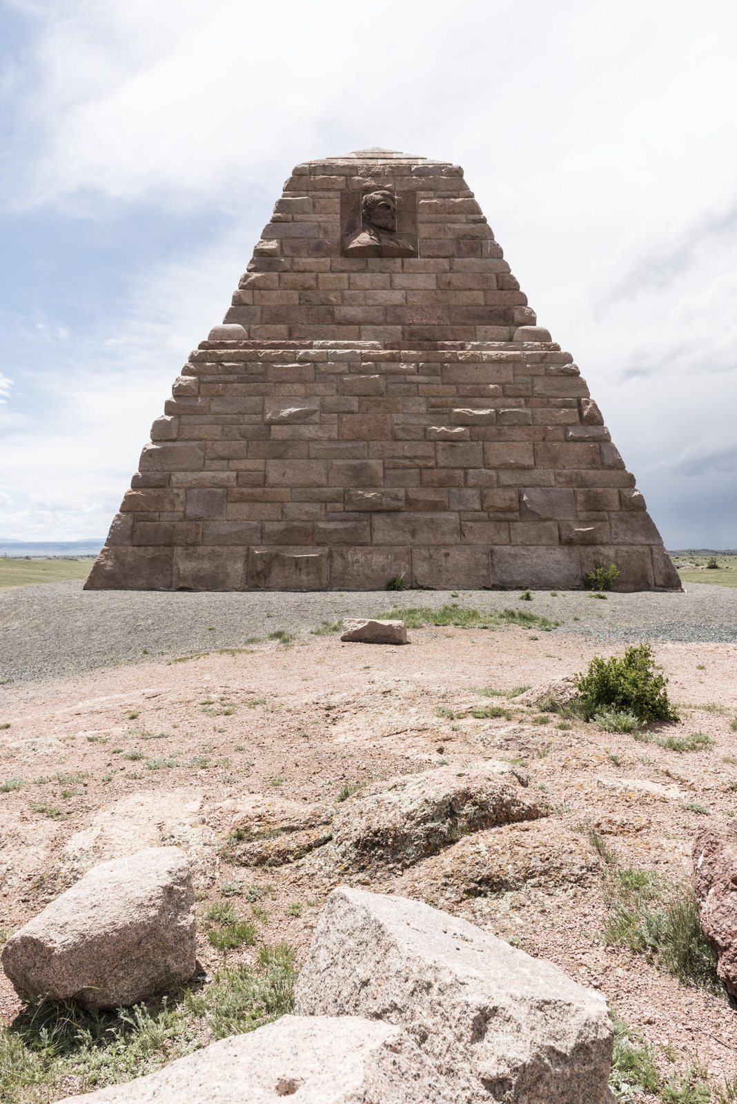 The Ames Monument, a four-sided granite pyramid with a carved portrait medallion near its apex, standing on bare rocky prairie in Albany County, Wyoming.