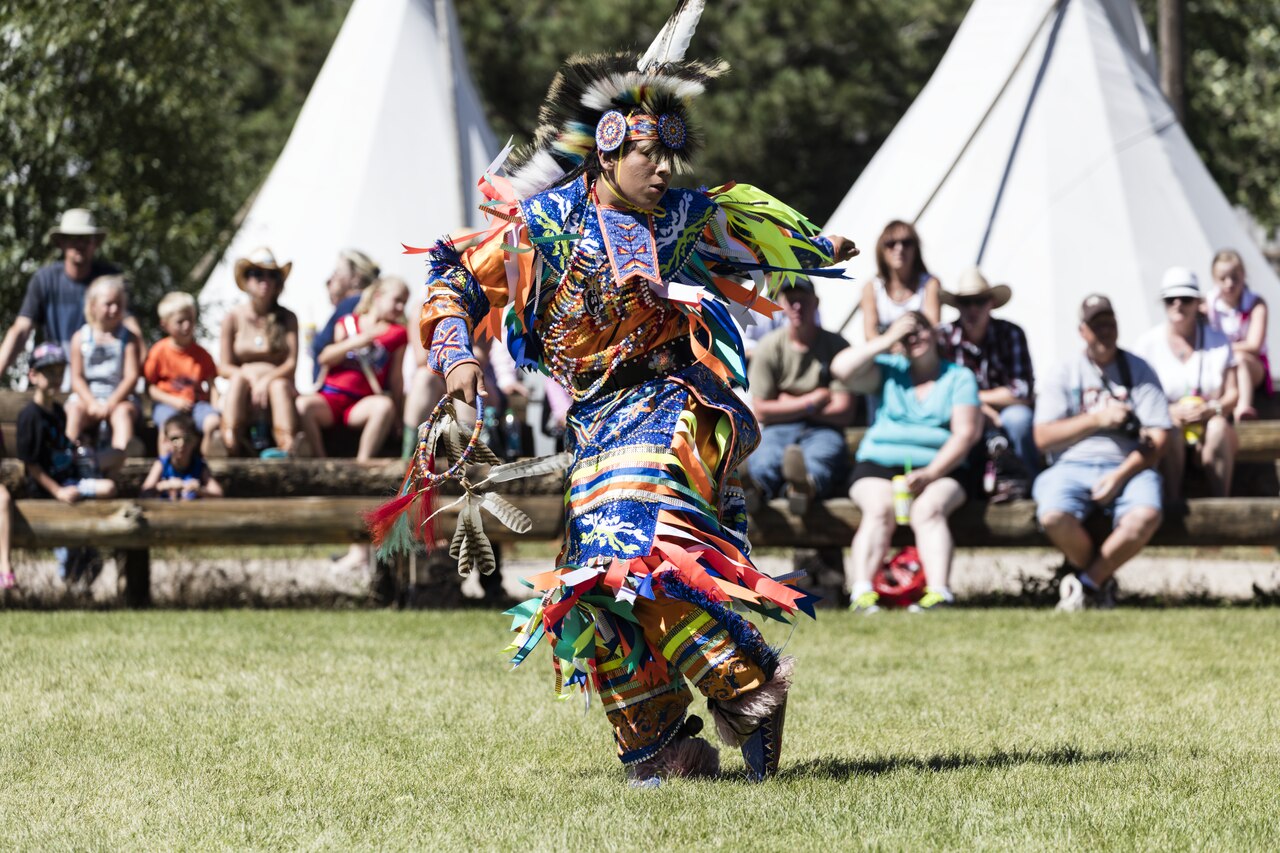 Native American performers in traditional dress at the Indian Village on the Cheyenne Frontier Days rodeo grounds, with spectators watching traditional dances.