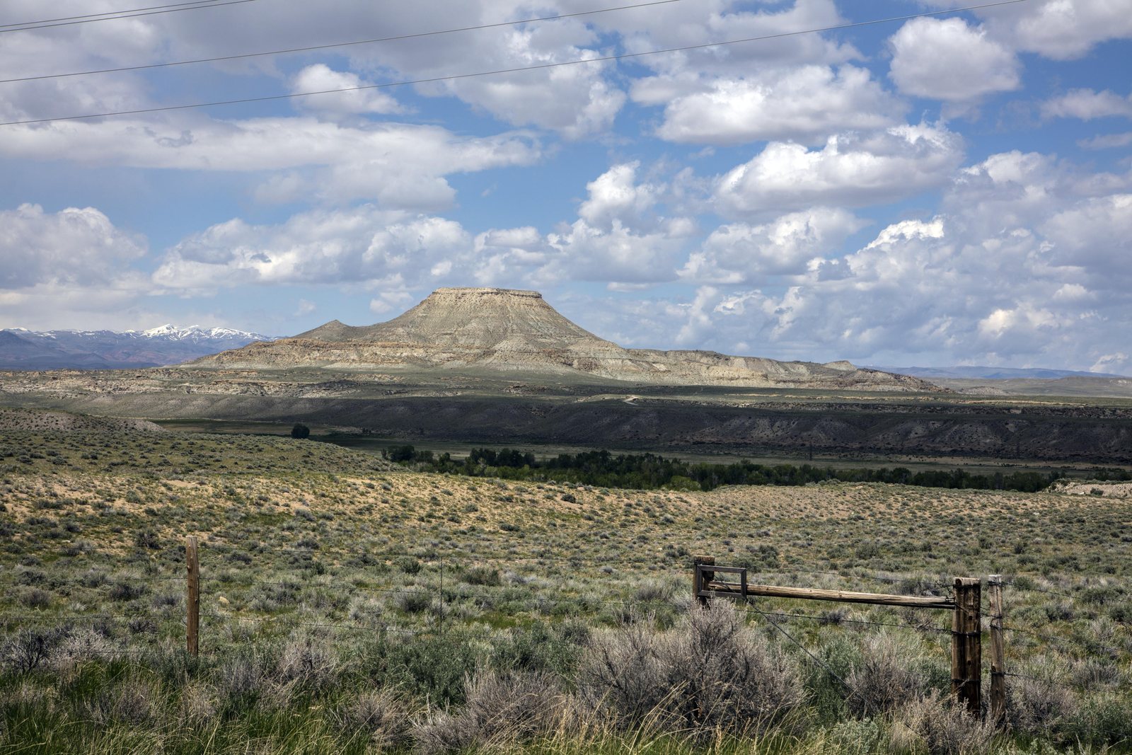 Crowheart Butte, a flat-topped bluff standing above sagebrush flats behind a weathered wooden fence, Fremont County, Wyoming.