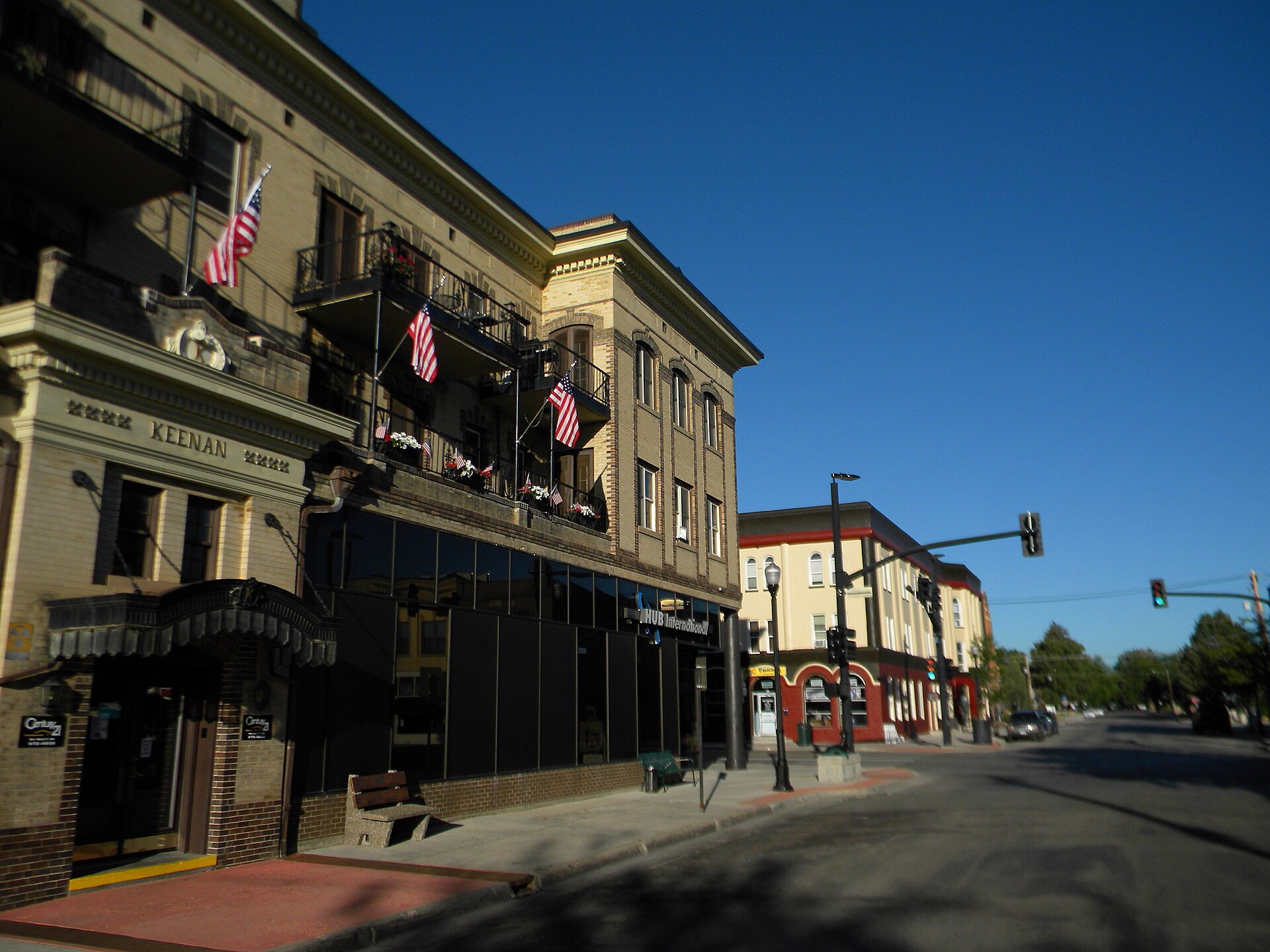 Main Street in Sheridan, Wyoming, with historic brick storefronts, the marquee of the Mint Bar, and the Bighorn Mountains visible in the distance.