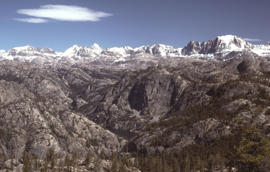 Pack string descending a switchback above an alpine lake in the Wind River Range, Wyoming, with granite peaks in the background.